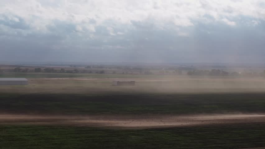 Dust storm blowing across an open highway in Oklahoma with distant hills and clouds