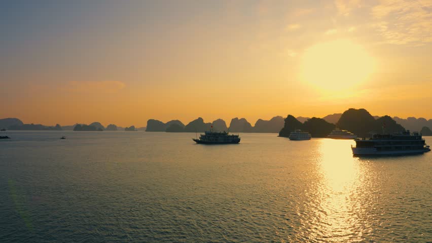 Aerial Landscape of many cruise ships anchored at Halong Bay backlit with rising bright sun, Vietnam