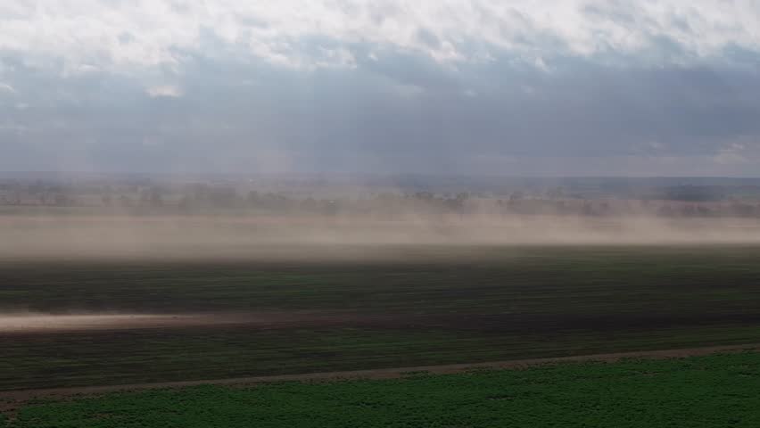 Dust blowing across fields with a wide, open sky in Oklahoma, driven by strong winds