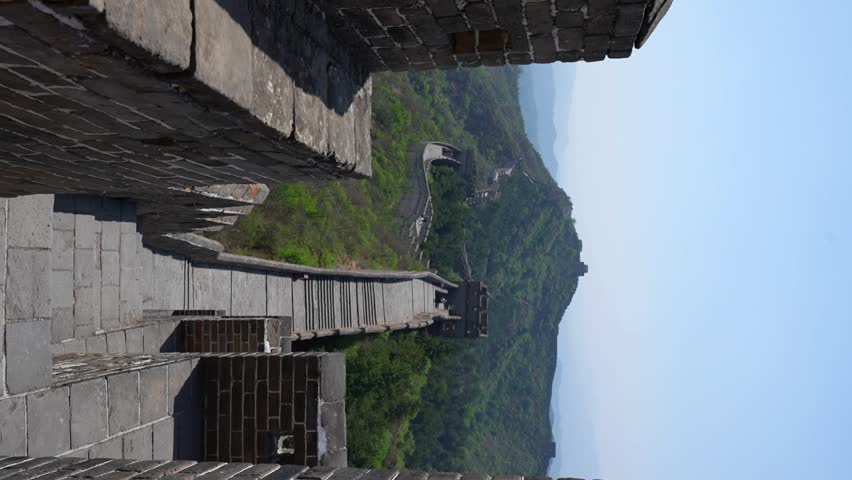 Vertical handheld view of the Great Wall at Jinshanling with greenery in the mountains