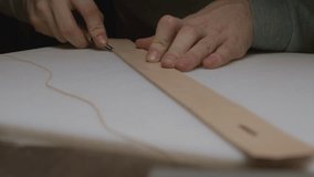 A craftsman cuts off excess leather from the brim of a raw leather belt. Focus shifting with his hands. - Powered by Shutterstock - Get 15% off with code: PIKWIZARD15