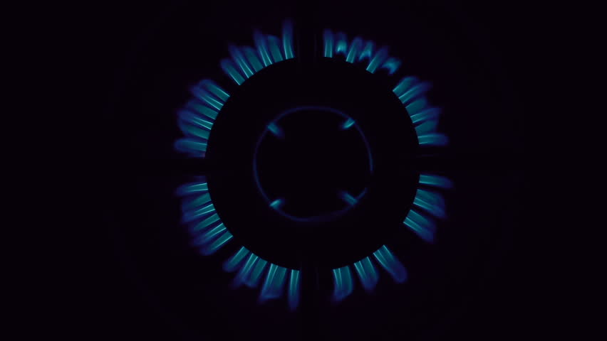 Closeup shot of blue fire from domestic kitchen stove top. Gas cooker with burning flames of propane gas. Industrial resources and economy concept.