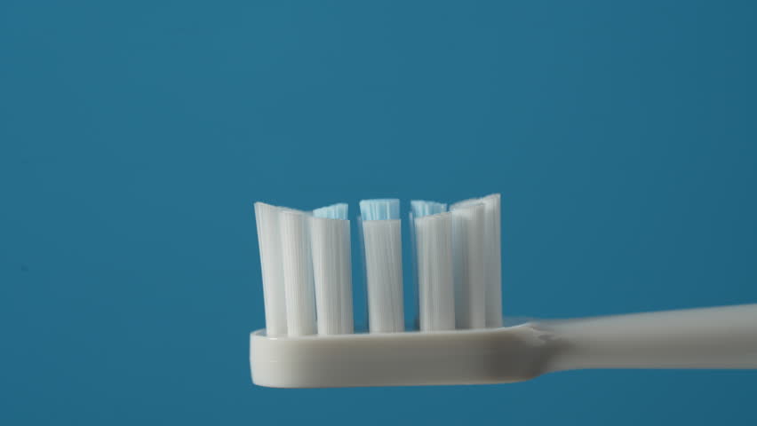 Toothpaste squeezed on the white toothbrush on blue background, close up. Dental care and hygiene tooth concept