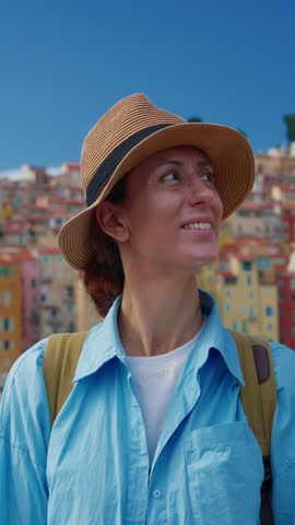 Beautiful woman in a hat stands in the background colorful houses in Menton, France. Cote d'Azur, France