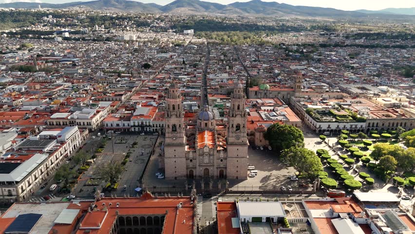 Morelia, Mexico - January 14, 2025: Cathedral and panoramic view of the city with mountains in the background during the afternoon. Drone camera approaches descending on the church facade