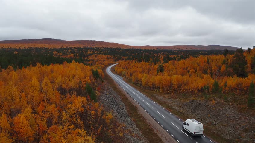Winding road through colorful autumn trees in Vestarelen, Norway, with RV