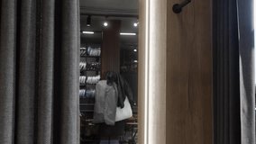 Elegant businessman adjusting his suit jacket while looking in the mirror in the dressing room of a menswear store, choosing his outfit for a special occasion or business meeting - Powered by Shutterstock - Get 15% off with code: PIKWIZARD15
