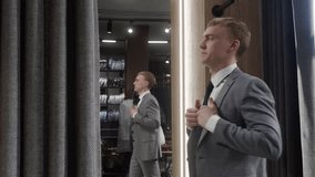 Elegant businessman adjusting his suit jacket while looking in the mirror in the dressing room of a menswear store, choosing his outfit for a special occasion or business meeting - Powered by Shutterstock - Get 15% off with code: PIKWIZARD15