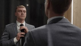 Young businessman in a suit adjusting his tie in front of a mirror, preparing for a business meeting or presentation, concept of self confidence and preparation in the business world - Powered by Shutterstock - Get 15% off with code: PIKWIZARD15