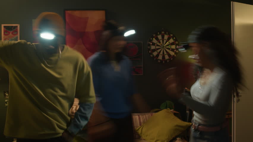 Freeze effect shot of three diverse male and female friends wearing headlamps dancing in dorm room