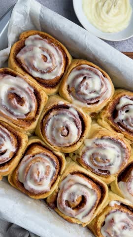 Freshly baked cinnamon rolls, topped with cream cheese frosting and almond flakes, create a tempting display