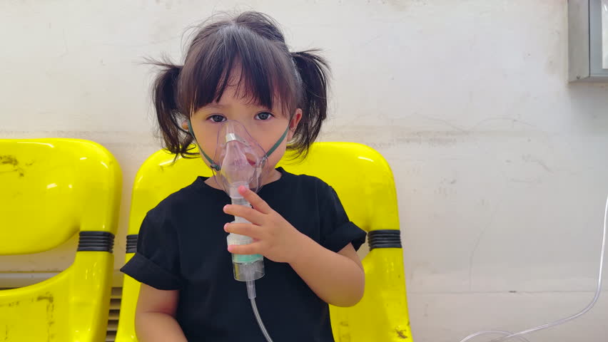 sick toddler baby girl using steam inhaler with nebulizer mask inhalation oneself in hospital