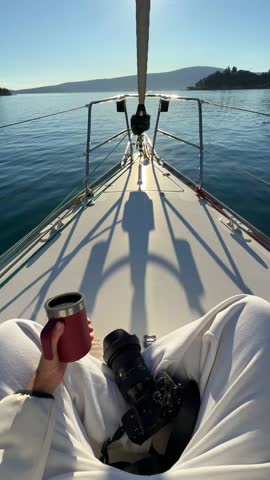 Woman hands holding thermo mug sitting on bow of the yacht during sailing in the morning in winter time in Adriatic sea, relaxation in yachting time. High quality 4k footage
