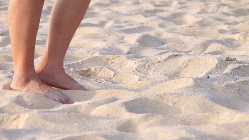 Person walking barefoot and kicking sand on Karon Beach, Phuket