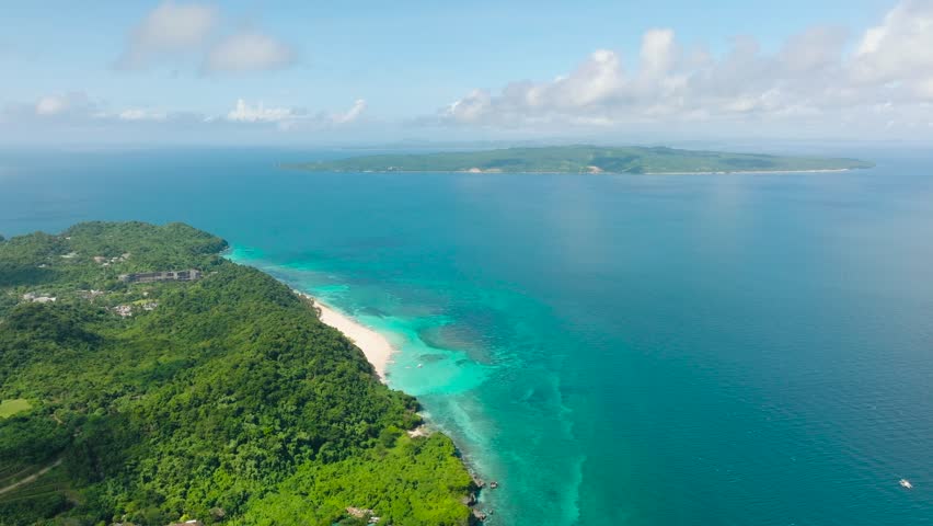 Tropical coastline with turquoise water, lush greenery, and scenic sandy beaches stretching along the shore. Boracay Island, Philippines.