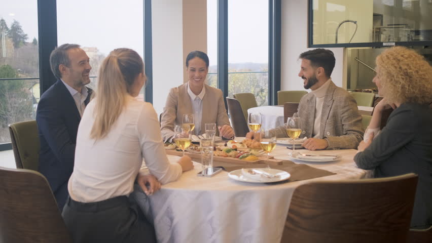 Smiling coworkers in restaurant toasting with wine during business lunch.