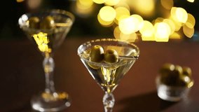  A close-up of a martini glass garnished with olives, set in a dimly lit lounge with a cozy and elegant ambiance. - Powered by Shutterstock - Get 15% off with code: PIKWIZARD15