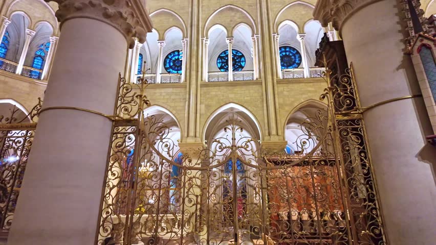 Beautifully gilded golden altar inside the Notre Dame cathedral under ornate stained-glass windows, Paris, France.