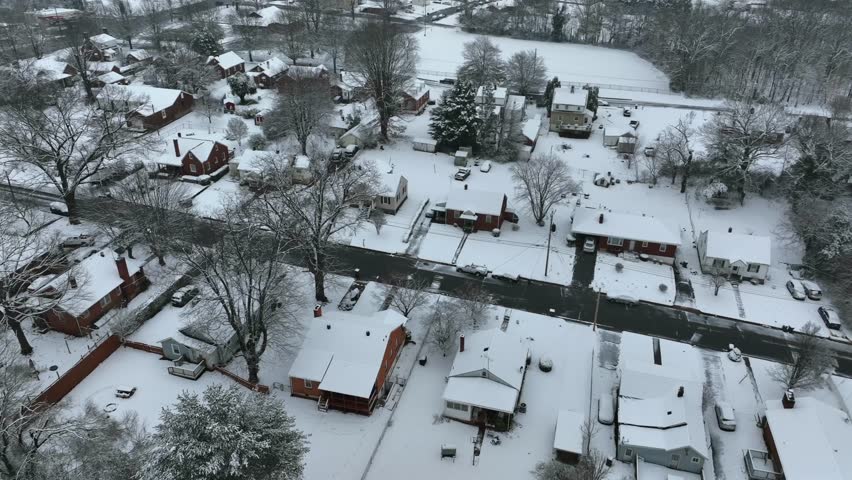 Snow-covered homes and houses in american suburb at winter snow. Parking snow capped cars. Aerial top down approach over housing area in USA. Lynchburg, Virginia.