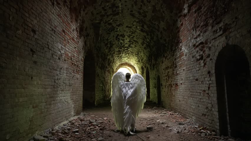 Figure with angel wings in an abandoned tunnel. Faith and religion concept.