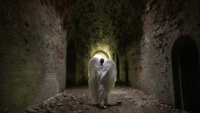 Figure with angel wings in an abandoned tunnel. Faith and religion concept. - Powered by Shutterstock - Get 15% off with code: PIKWIZARD15