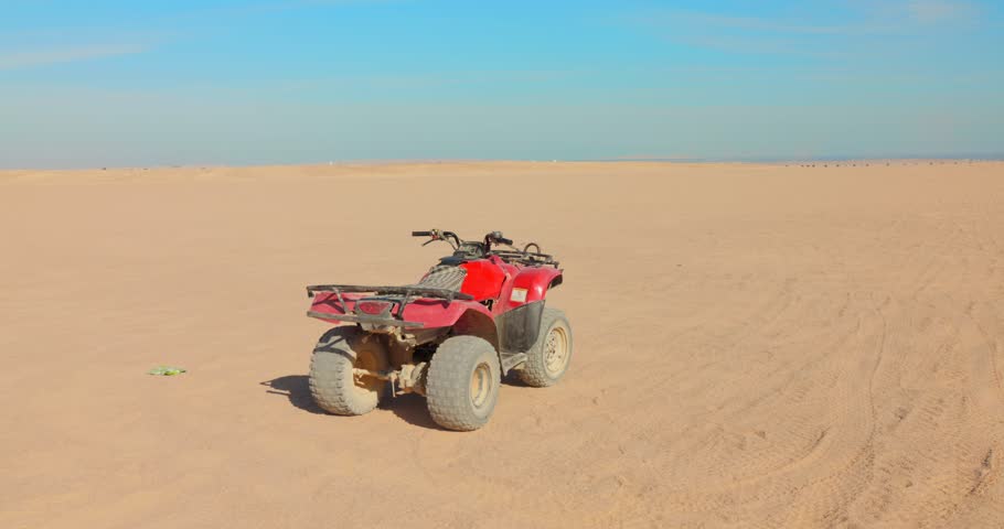 Quad bike parked in the vast desert under a clear blue sky, adventure and solitude
