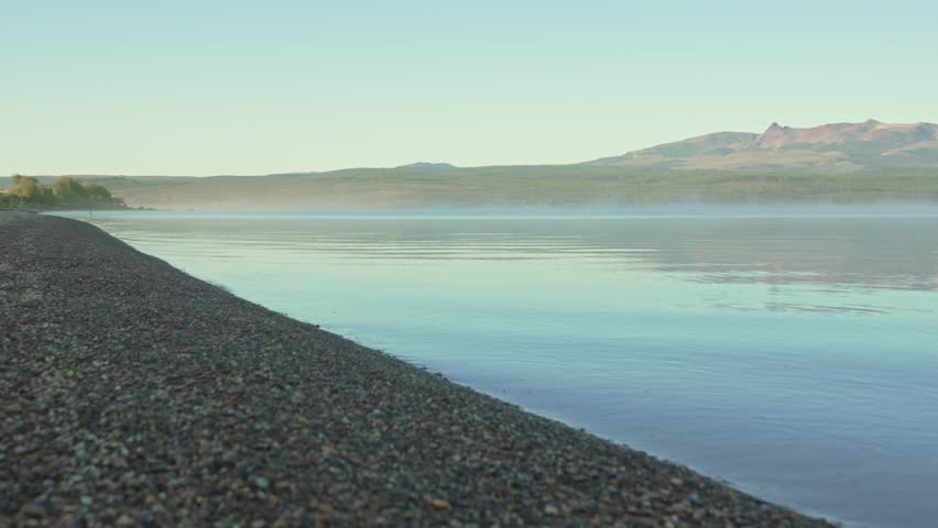 Calm Alumine Lake shoreline in Neuquén, Argentina, with still water and distant mountains