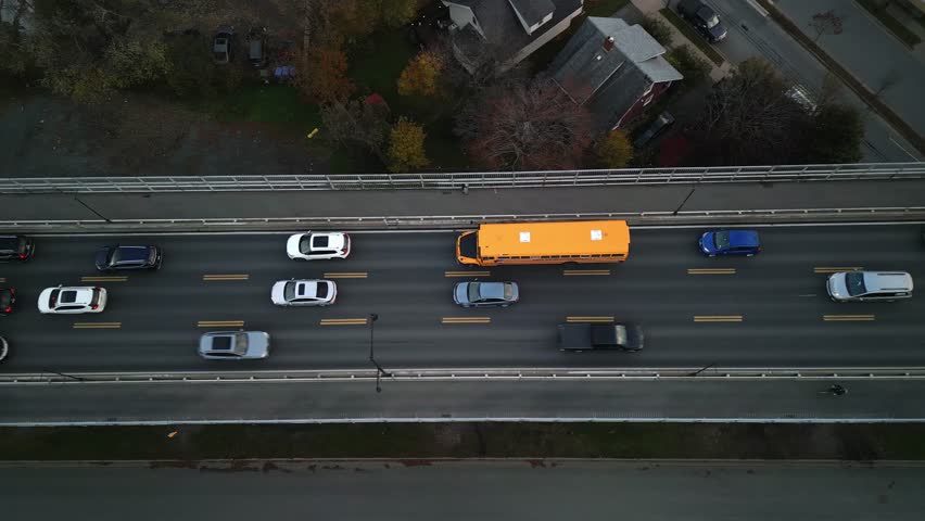 Aerial View Yellow School Bus Traveling Over Bridge Between Halifax And Dartmouth, Nova Scotia. Bright Summer Day Sets A Peaceful Scene, Showcasing The Route Through This Beautiful Canadian Landscape 