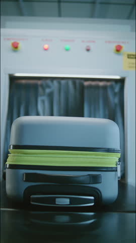 Security Checkpoint in Modern Airport Terminal: Passenger Takes Suitcase from Conveyor Belt with Advanced X-ray Scanning Metal Detector. Baggage Scanning Procedure for Boarding Flight. Vertical Shot.