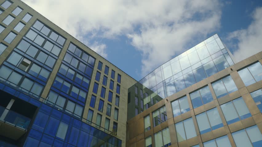 Low Angle View of Modern Glass Buildings with Blue Sky and White Clouds 4K