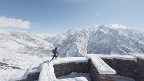 Winter Trekker Exploring Ancient Ruins in the Armenian Mountains. A hiker equipped for winter trekking walks along the snow-covered ruins of an ancient stone fortress - Powered by Shutterstock - Get 15% off with code: PIKWIZARD15