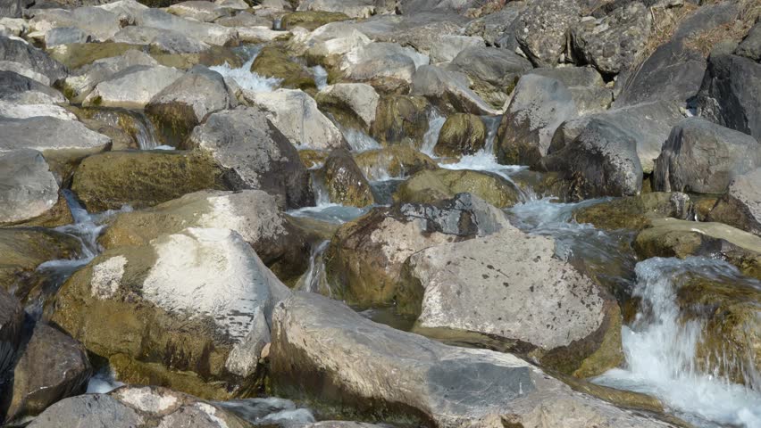 Water gently cascades over rocks in the Swiss Alps near Walensee, creating a soothing and peaceful scene that highlights the natural beauty and tranquility of the alpine landscape.