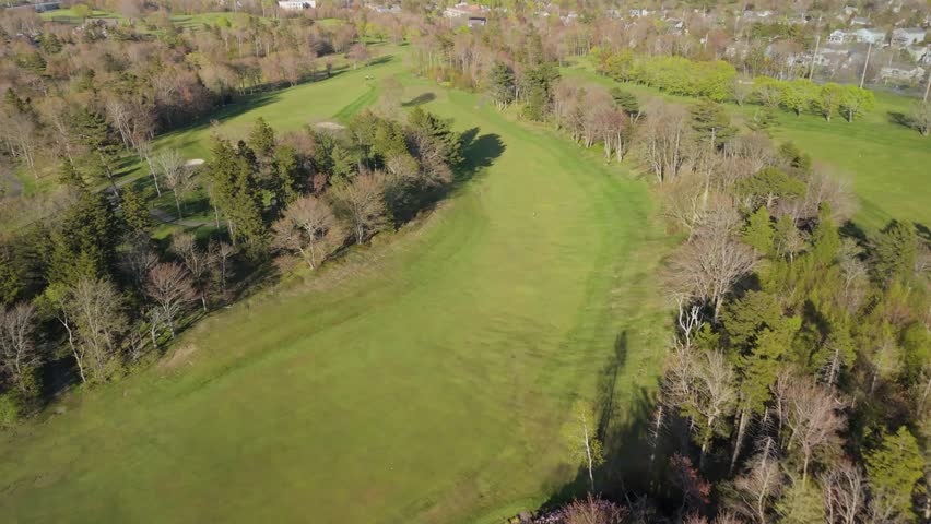 Stunning Aerial Shot Of A Golf Course, Featuring Players On The Green And Groundskeepers Maintaining The Field. The Scene Captures The Interplay Between Athleticism And Careful Maintenance.