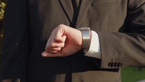 Businessman raises hand and looks at the smartwatch on it. Businessman is  checking time on the smartwatch. Close up, slow motion footage. Modern gadgets and people concept. Modern communication. - Powered by Shutterstock - Get 15% off with code: PIKWIZARD15
