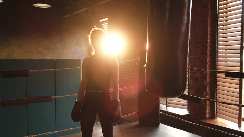 Woman fighter with boxing gloves standing on boxing ring celebrating victory. Woman boxing champion showing raising hands up. Strong powerful girl on boxing ring arena. Competition champion winner