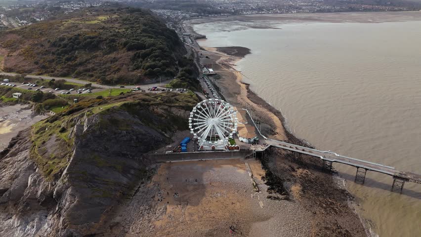 Aerial pull back shot of The Big Wheel at Mumbles Pier Swansea on a sunny day in United Kingdom.