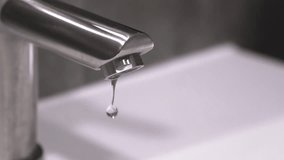 Water droplets steadily dripping from modern, stainless steel faucet spout, highlighting plumbing problems, water waste, and need for repair or replacement - Powered by Shutterstock - Get 15% off with code: PIKWIZARD15