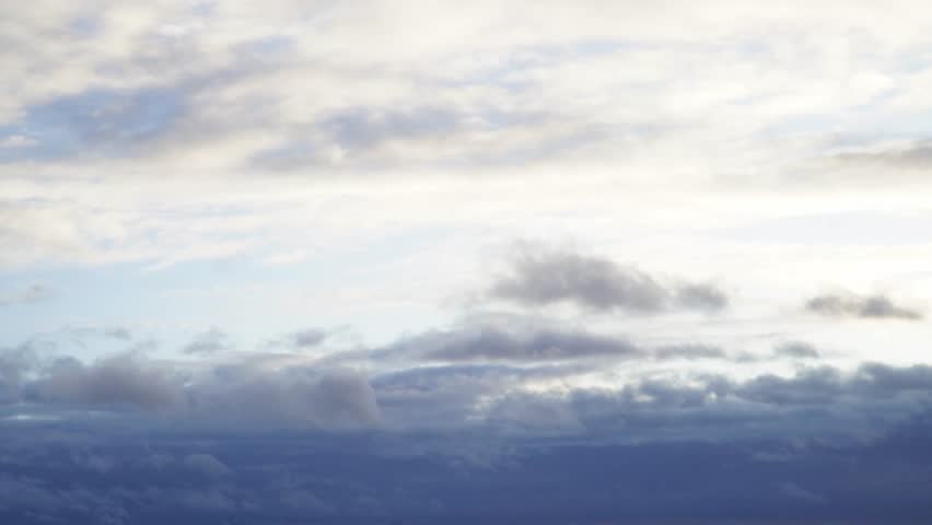 Stormy sky with dark, snowy clouds on a spring day. Clouds are floating across the sky. Dramatic clouds. Dark blue clouds swiftly floating across blue sky. Sky texture, abstract nature background.