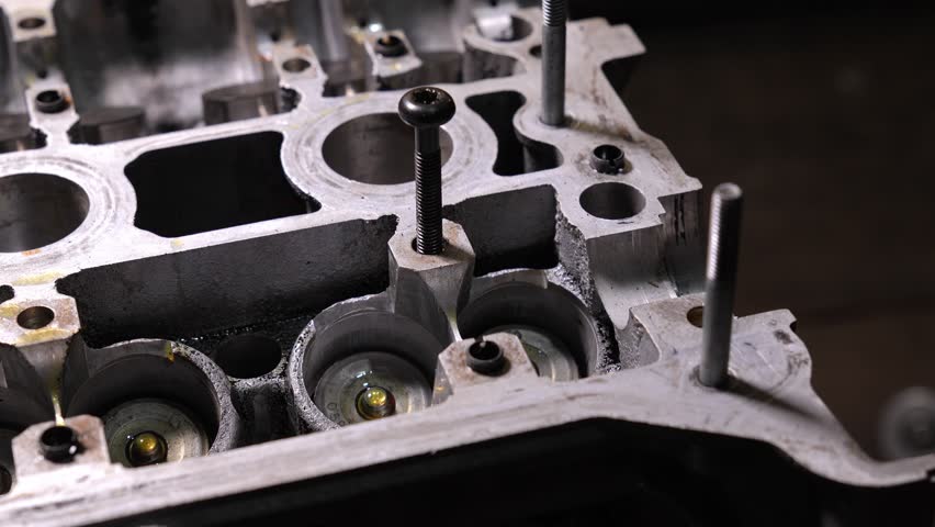 Gloved hands carefully install new hydraulic valve compensators on cylinder head of internal combustion engine,