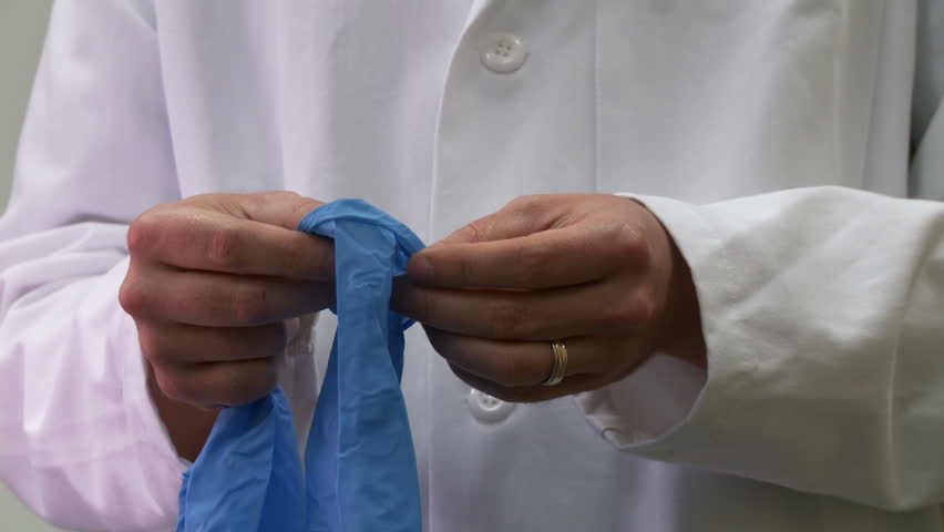 Scientist puts on a pair of protective blue rubber gloves.