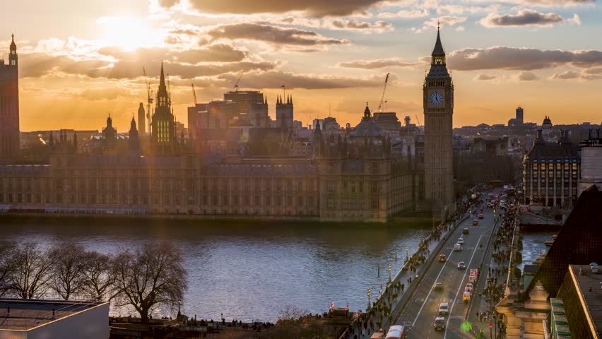 Elevated sunset to night time lapse view of the Westminster Palace and Big Ben clocktower in London with street and people traffic, England