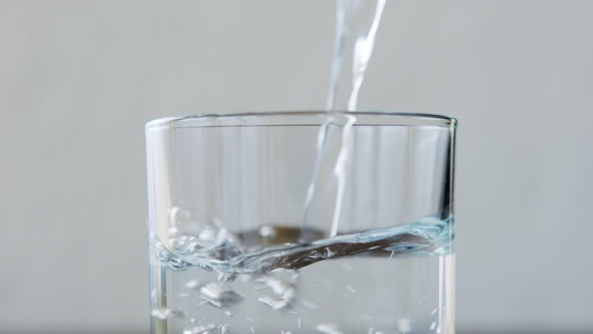 Drinking water pouring into glass close-up.