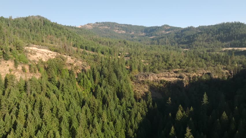 Aerial 4K footage showcasing the scenic beauty of Prospect, Oregon, and the Rogue River in October. Stunning views of lush evergreen forests, rugged terrain, and a winding river under clear skies.