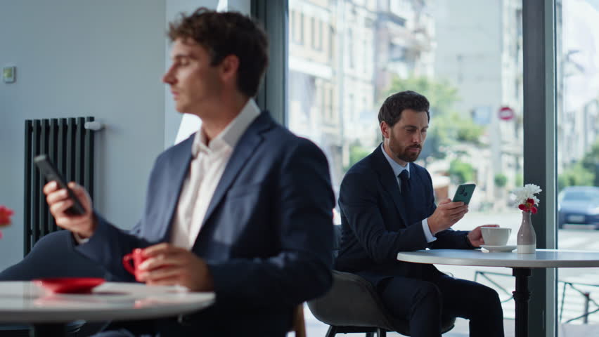 Relaxed ceo enjoying espresso sitting at office canteen closeup. Resting colleagues holding mobile phones watching social media at coffee tables. Elegant people spending time work break in cafeteria
