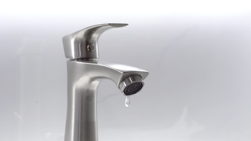 Closeup of water dripping from faucet tap at bathroom.
