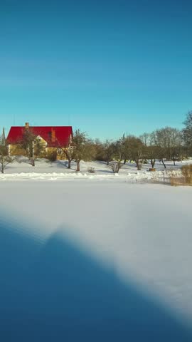 Vertical winter to summer time lapse shot of a cottage near a pond.