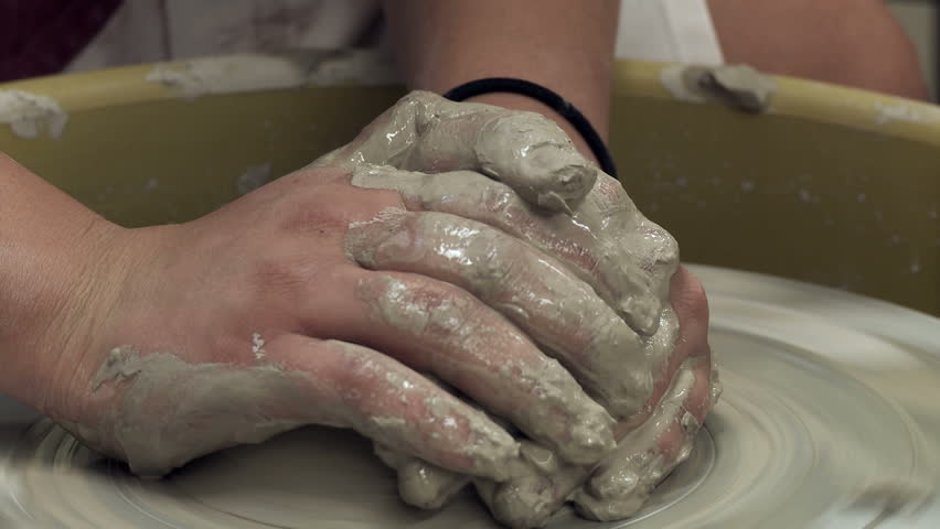 Hands shaping clay on a potter's wheel.