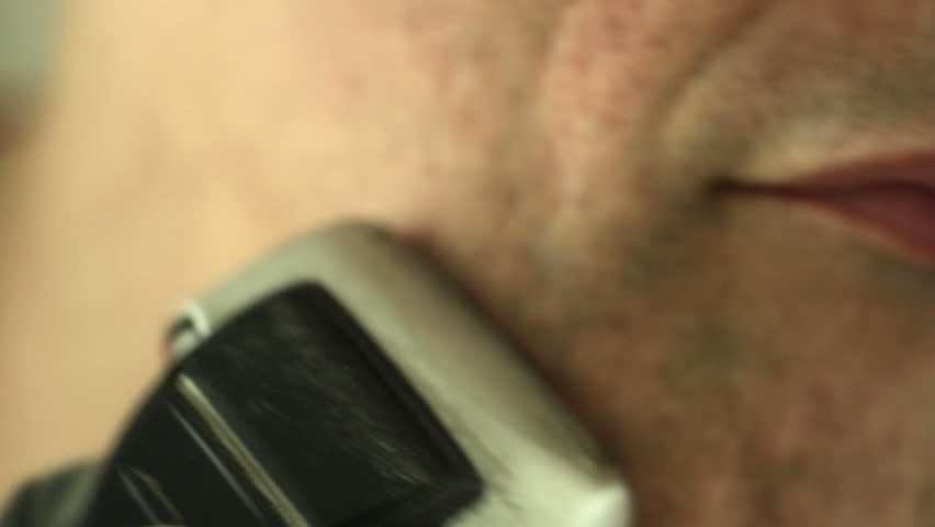 Man shaves his chin and face with an electric razor Shot with a macro lens and