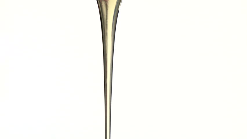 Runny golden honey pouring from a spoon against a white background. Live action