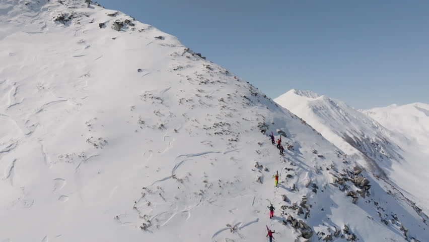 Group of mountain tourists climb snowy mountains in winter, aerial view